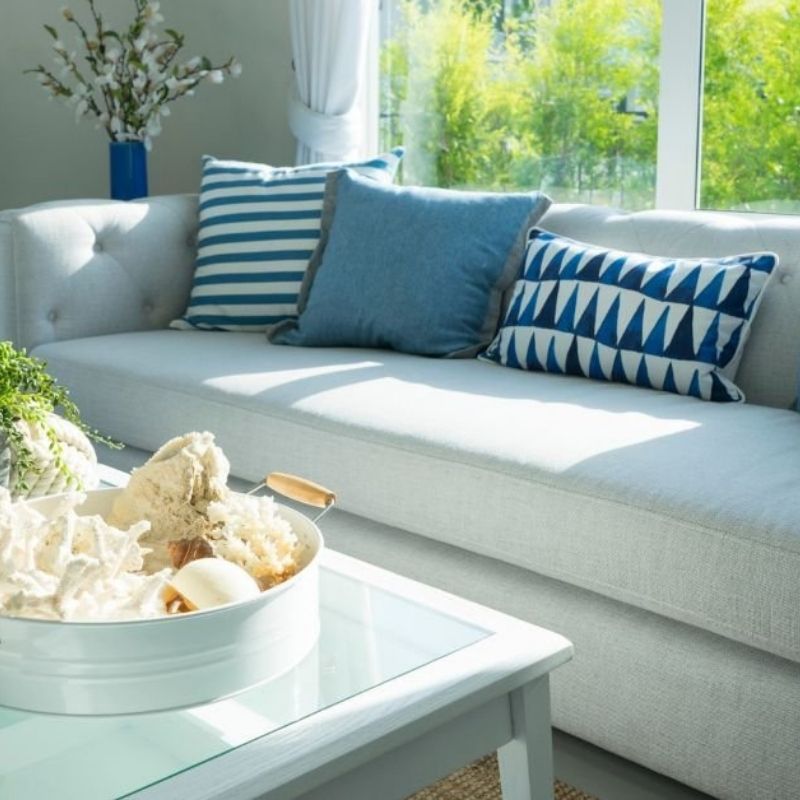 A white couch adorned with blue and white decorative pillows, creating a fresh and inviting living space.